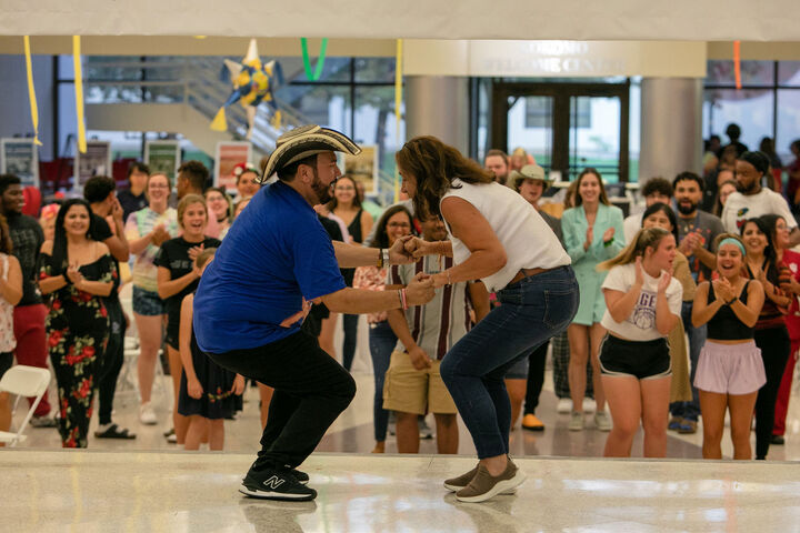 J.R. Pico, director of Latinos Unidos Hispanic Center, dances with a faculty member as joyful spectators watch.